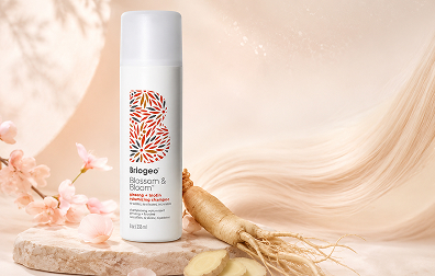 Briogeo Blossom & Bloom volumizing shampoo bottle displayed on a soft peach beauty background with ginseng root, delicate petals, and a smooth hair-like texture.Briogeo Blossom & Bloom volumizing shampoo bottle displayed on a soft peach beauty background with ginseng root, delicate petals, and a smooth hair-like texture.
